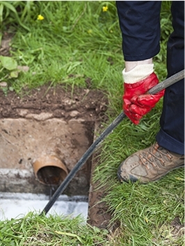 Professionnel qui débloque un drain d'égoût extérieur