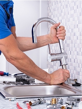 Homme en train de réparer un robinet de cuisine