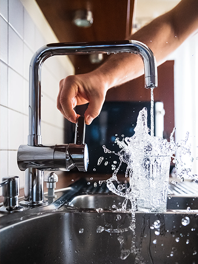 Robinet d'eau qui coule dans un verre et éclabousse