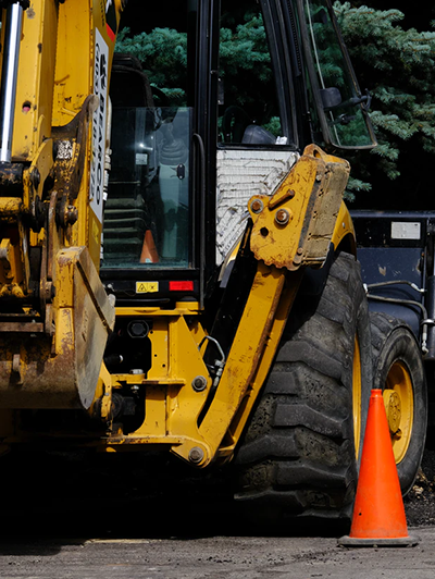 Tractopelle circulant sur un chantier délimité par un cône orange